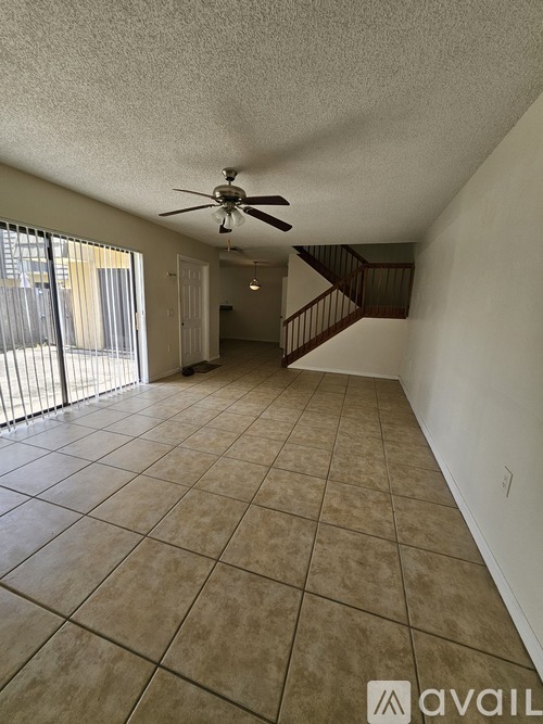 A spacious room with a fan and tiled flooring.