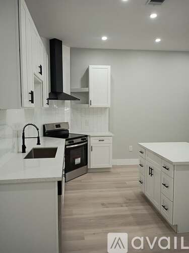 A kitchen with white cabinets and a black range hood.