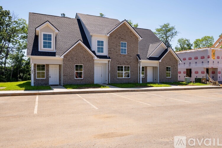 A large brick house with a parking lot in front.