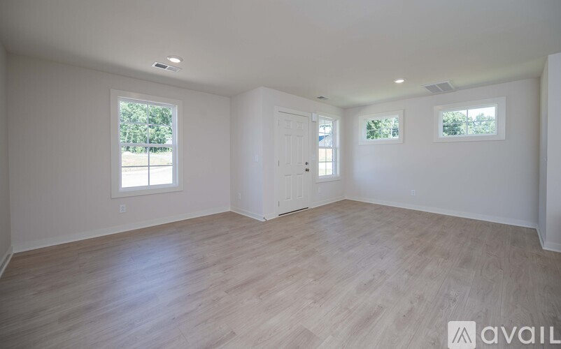 A spacious room with wooden flooring and white walls.