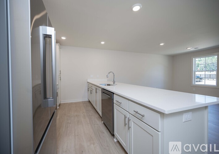 A modern kitchen with white cabinets and a stainless steel refrigerator.