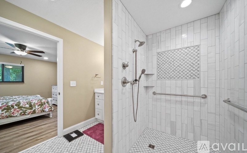 A bathroom with a shower and a bedroom with a bed and a window.