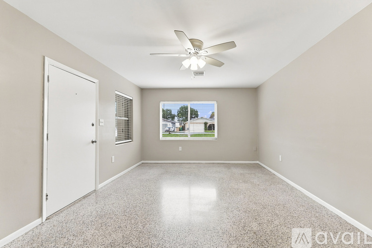 A spacious room with a ceiling fan and a window with blinds.
