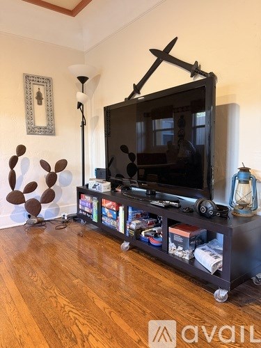 A black television is on a stand with a remote and a lamp.