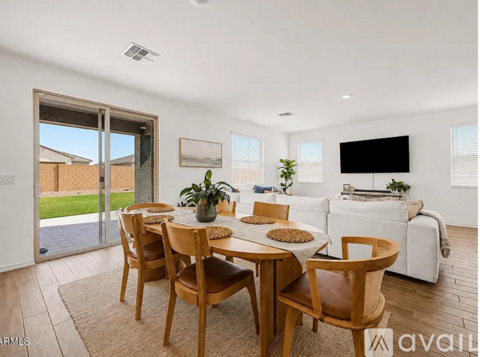 A modern dining room with a table set for four and a television in the corner.