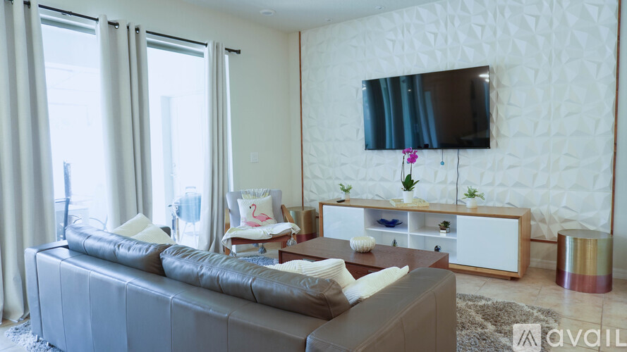 A living room with a grey couch and a television on the wall.