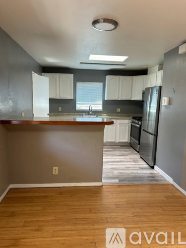 A kitchen with wooden floors and a refrigerator.