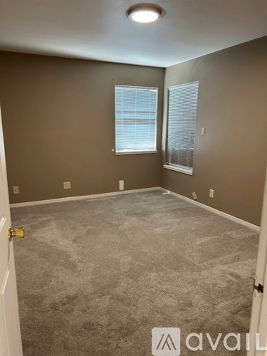 A room with a carpeted floor and a window with blinds.