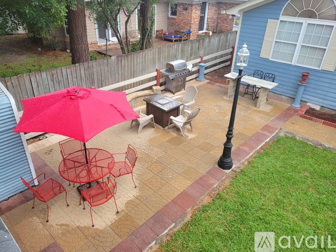 A patio with a red umbrella and chairs.