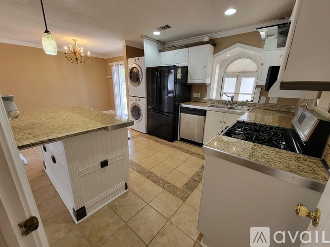 A kitchen with a granite countertop and a chandelier.