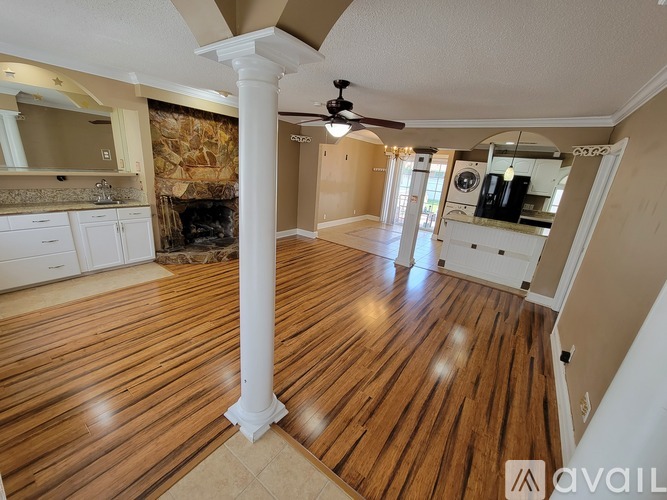 A spacious room with wooden flooring and a central column.
