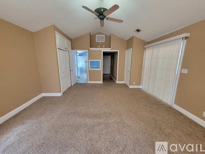 A room with a carpeted floor and a ceiling fan.