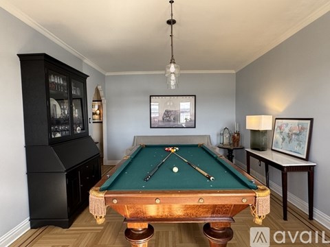 A pool table is in the middle of a room with a black cabinet and a picture frame on the wall.