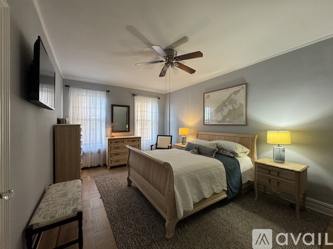 A bedroom with a bed, dresser, and a ceiling fan.