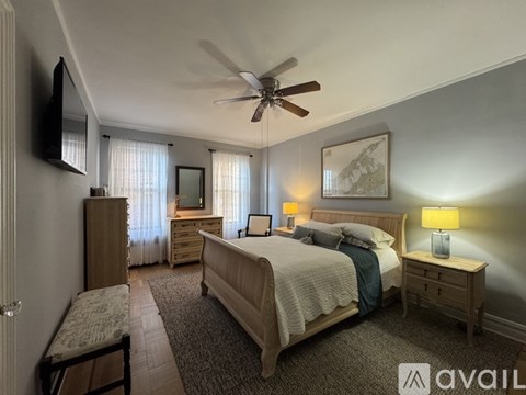 A bedroom with a bed, dresser, and a ceiling fan.
