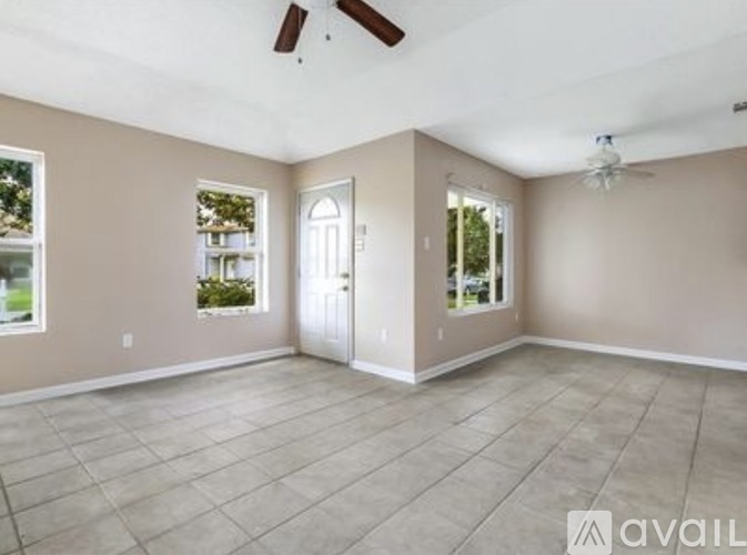 A spacious room with a ceiling fan and a door leading to another room.