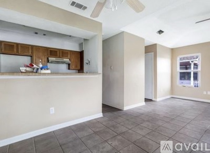 A spacious room with a kitchenette and a ceiling fan.