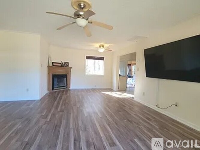A living room with a wooden floor and a ceiling fan.