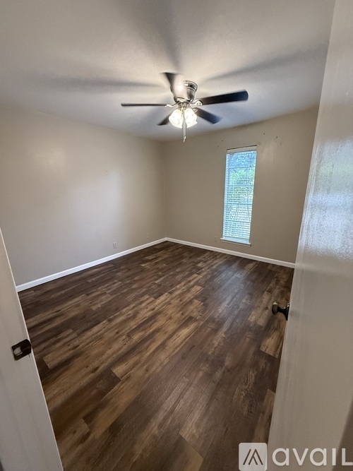 A room with a ceiling fan and wooden flooring.