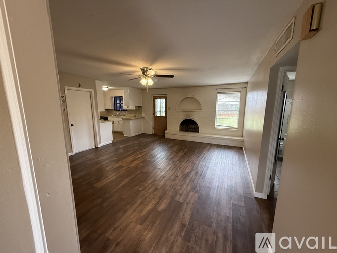 A spacious room with wooden floors and a ceiling fan.