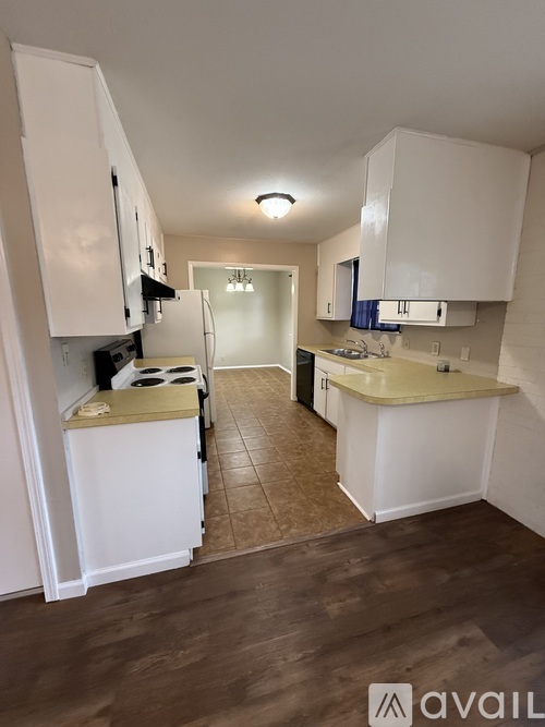A kitchen with white cabinets and a wooden floor.
