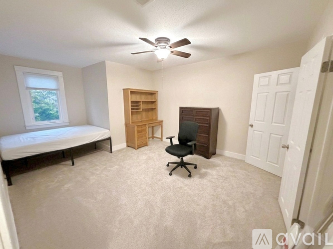 A bedroom with a bed, desk, and chair.
