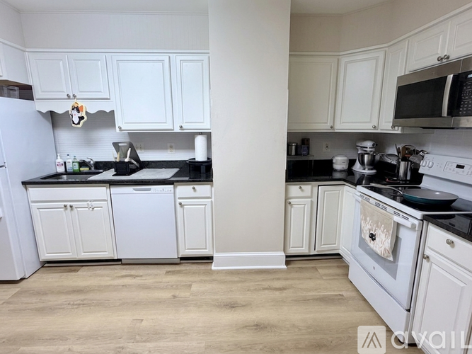 A kitchen with white cabinets and black countertops.