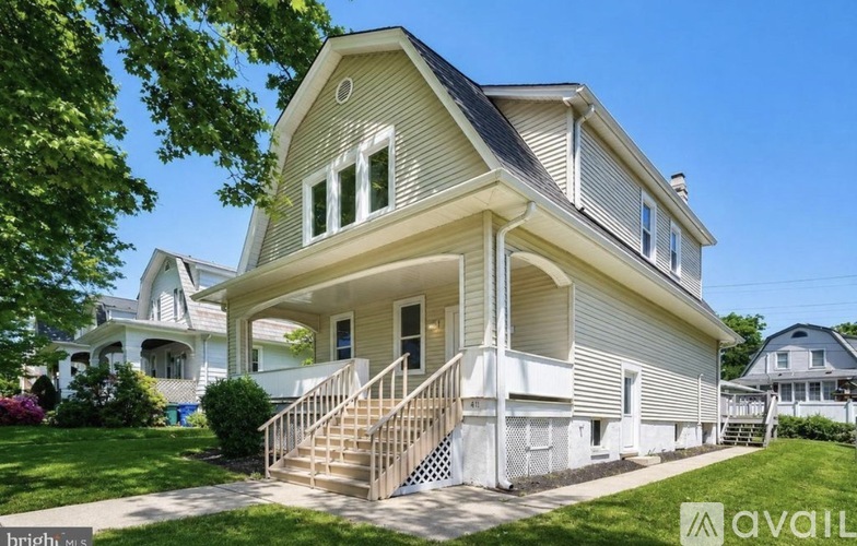 A two-story house with a front porch and a staircase leading to the entrance.