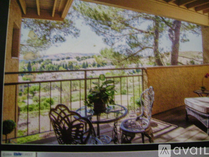 A balcony with a table and chairs overlooking a landscape.