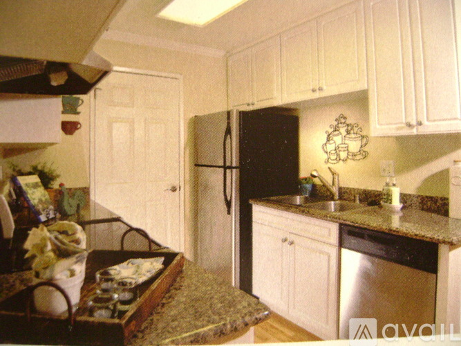 A kitchen with a black fridge and white cabinets.