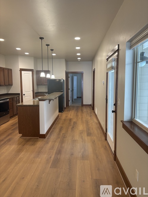 A modern kitchen with wooden floors and a white island.