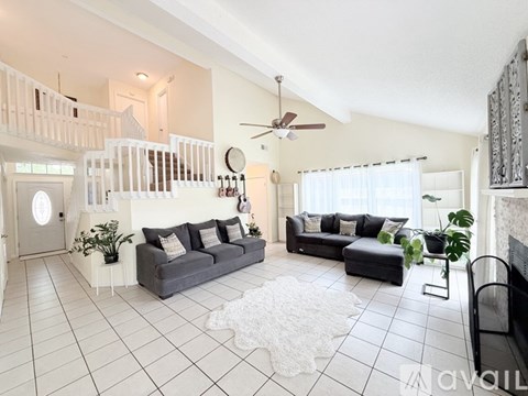 A living room with a grey couch and a white rug.