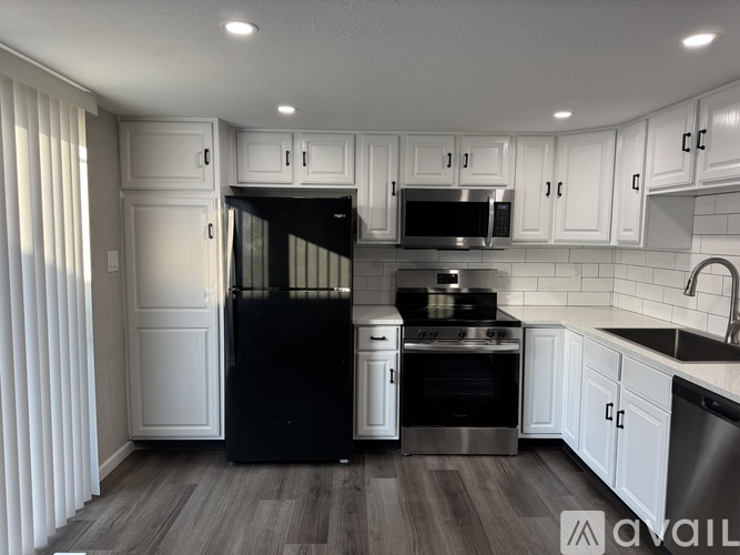 A kitchen with black appliances and white cabinets.
