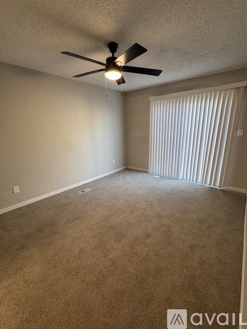 A room with a ceiling fan and carpeted floor.