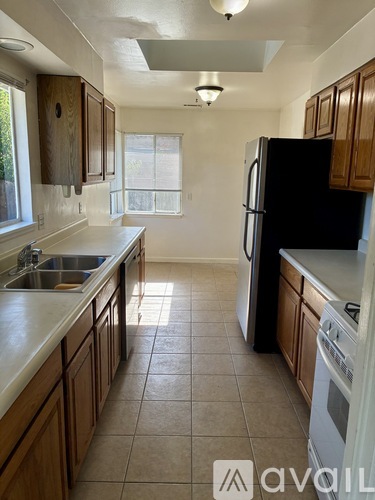 A kitchen with a black refrigerator and brown cabinets.