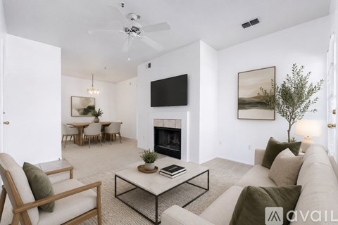 A living room with a fireplace, a couch, a chair, a coffee table, and a painting on the wall.