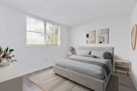 A bedroom with a large bed and a window with blinds.