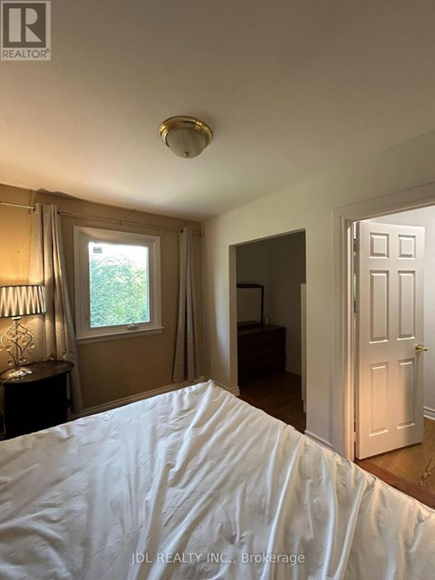 A bedroom with a bed in the foreground and a window with curtains.