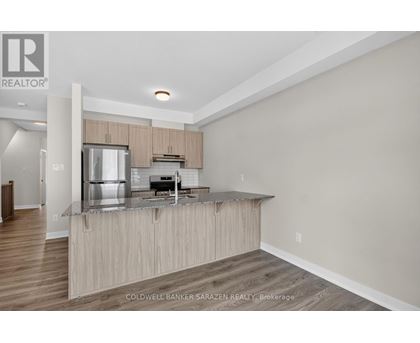 A modern kitchen with wooden cabinets and a stainless steel refrigerator.