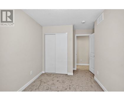 A bedroom with a white closet and carpeted floor.