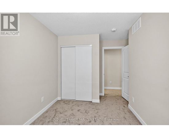 A bedroom with a white closet and carpeted floor.