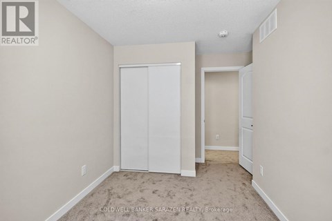 A bedroom with a white closet and carpeted floor.