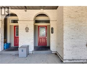 A white building with a red door and a small grey box in front.