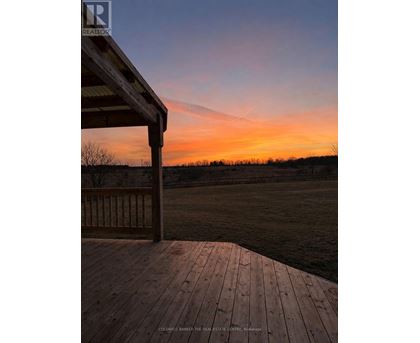 A wooden deck overlooks a field at sunset.