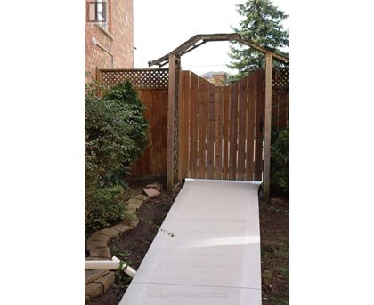 A wooden fence with a gate and a concrete pathway leading to it.