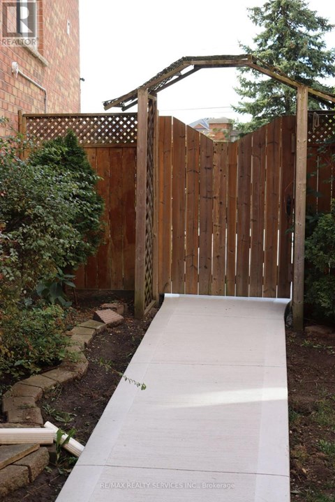 A wooden fence with a gate and a concrete pathway leading to it.