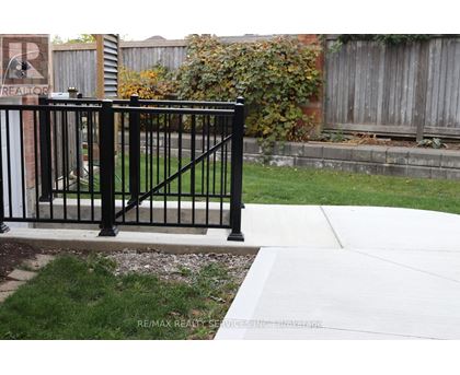 A black metal fence in front of a brick wall.