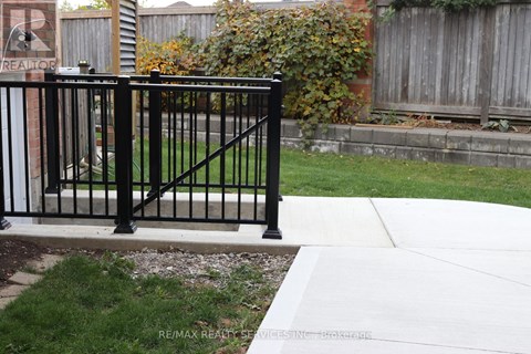 A black metal fence in front of a brick wall.