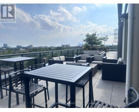 A patio with a table and chairs overlooking a cityscape.