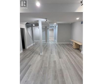 A spacious room with grey flooring and white walls, with a bench on the right side.
